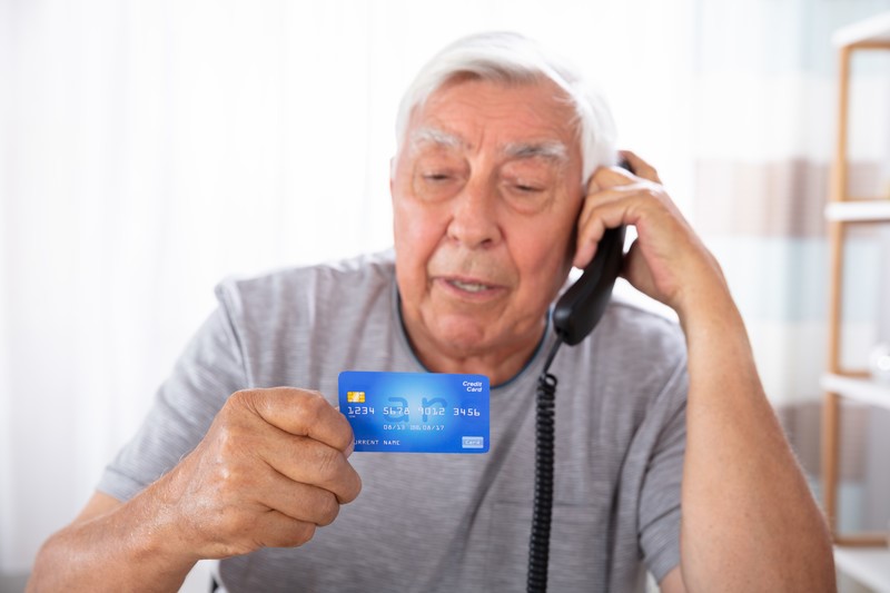 Older man with a credit card and phone in Dallas, TX